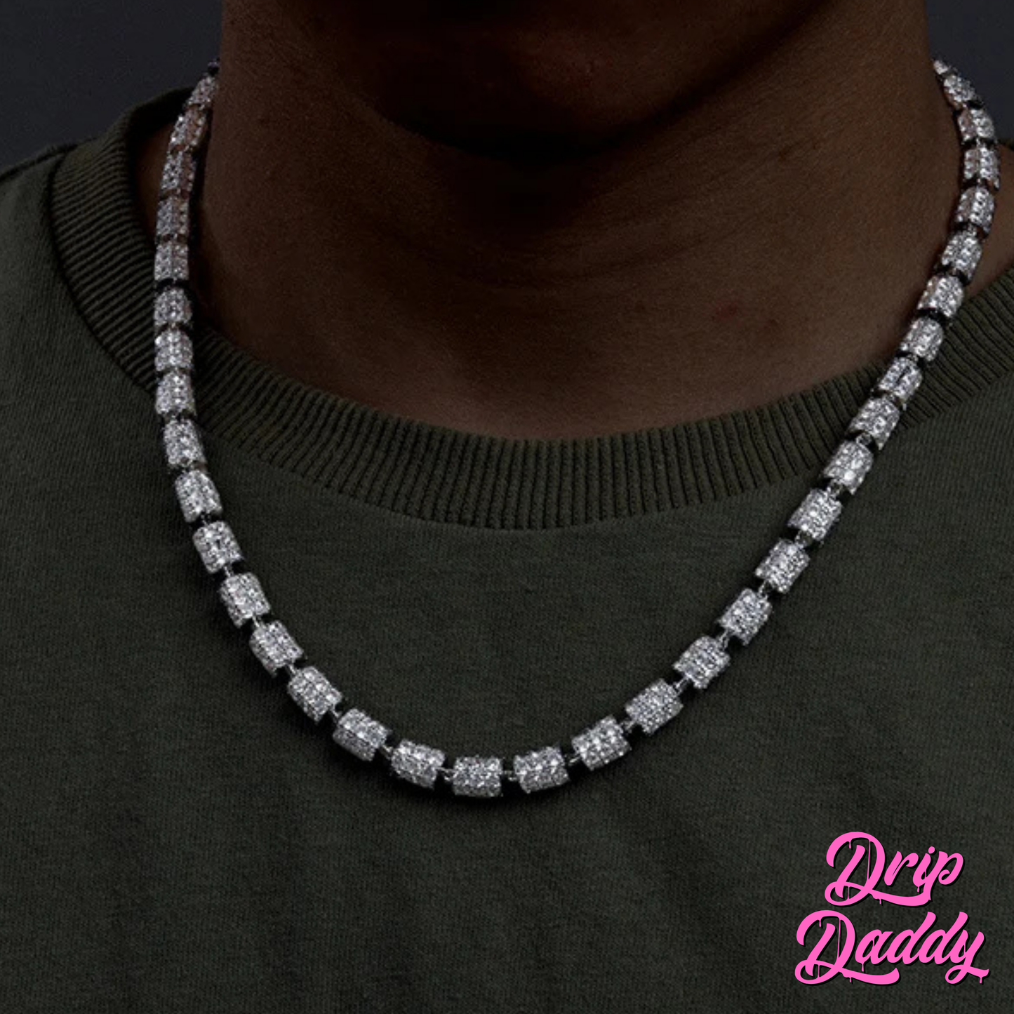 A person wearing Drip Daddy’s Stargazer Cylinder – 7mm Moissanite Chain in white and yellow gold plating, styled around the neck with an olive green shirt, with the Drip Daddy logo visible in pink at the bottom right corner.