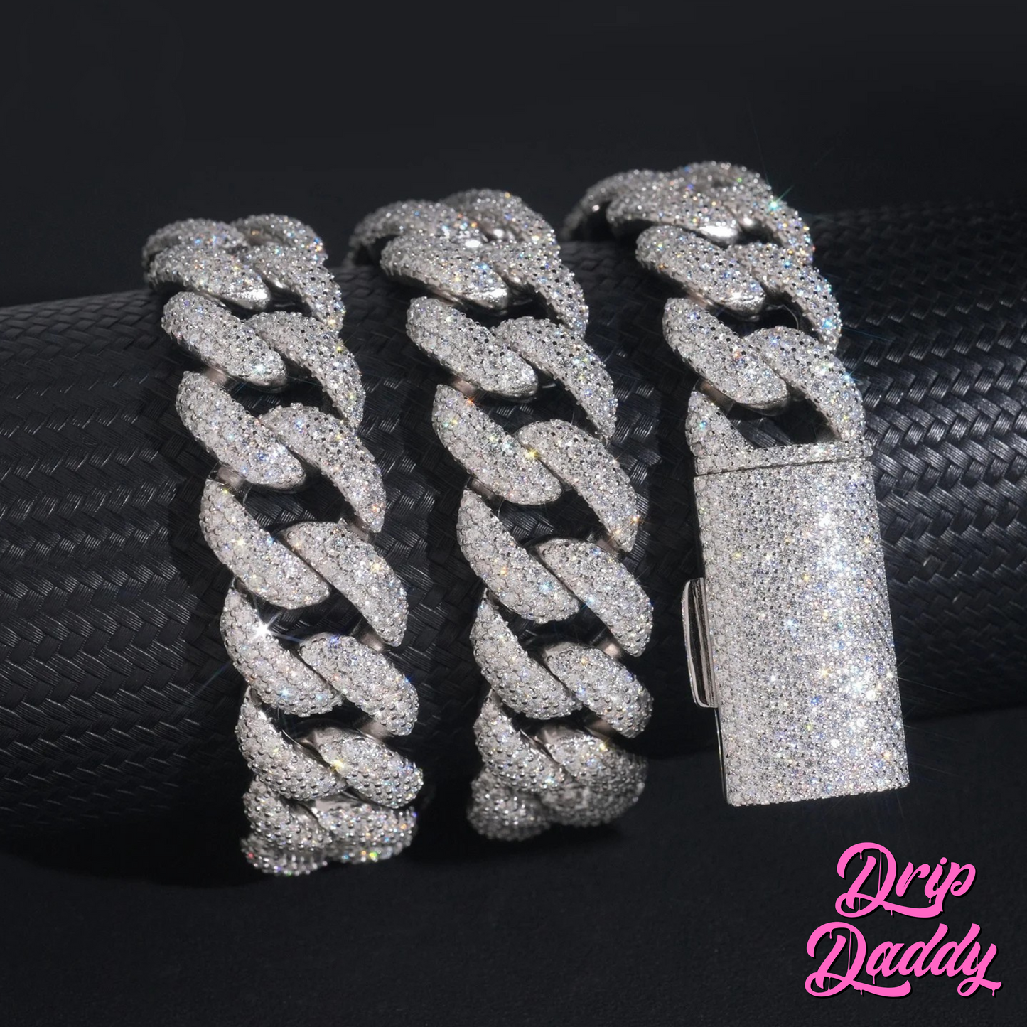 Close-up of Drip Daddy’s The Heavy Hitter 20mm to 30mm Moissanite Miami Cuban Link Chain in white gold plated finish, with focus on the fully iced-out clasp detail, shown wrapped around a black textured cylinder, with the Drip Daddy logo in pink in the bottom right corner.
