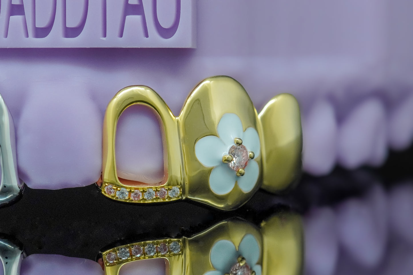 Custom gold grillz with flower enamel design, pink gemstone center, and diamond accents by Drip Daddy.