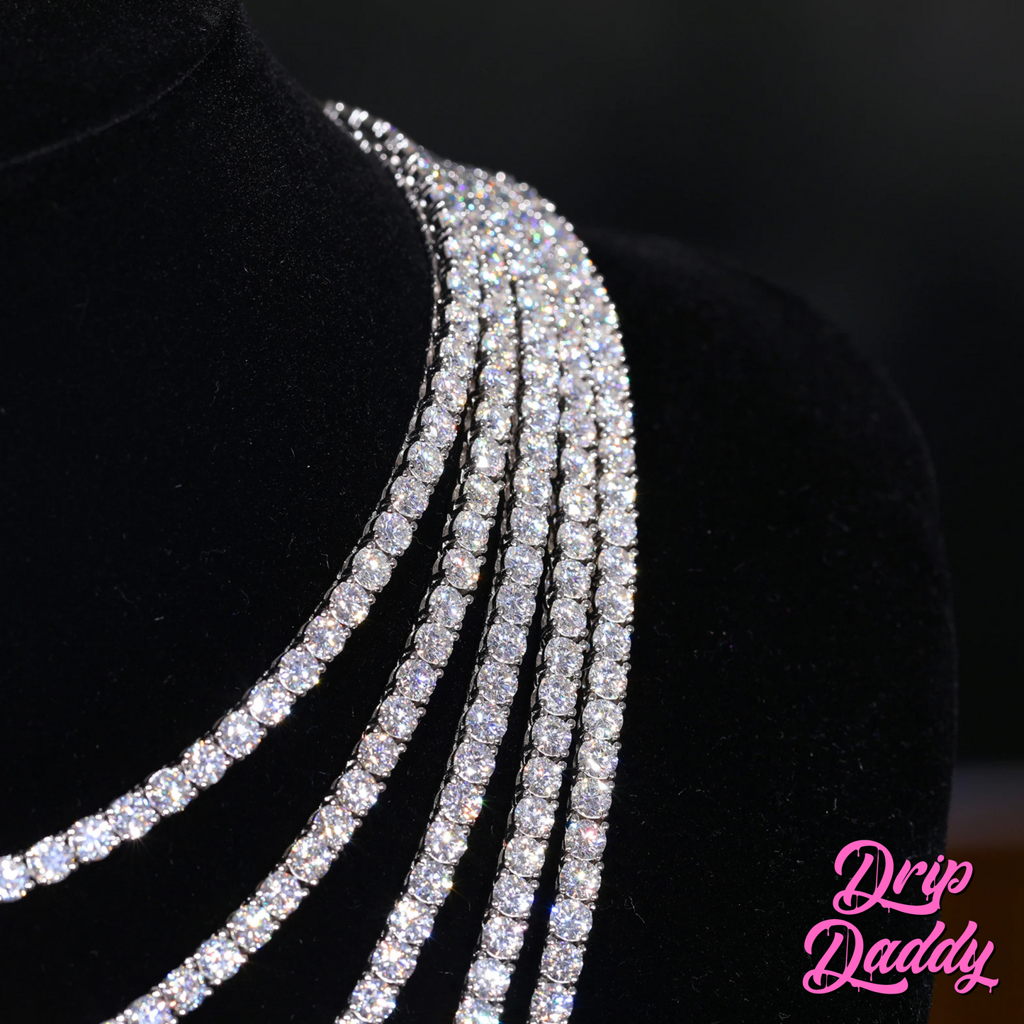 Four Moissanite Tennis Chains (3mm-6mm, White, Yellow & Rose Gold Plated) by Drip Daddy are displayed on a black velvet bust; the pink Drip Daddy logo appears in the bottom right corner.