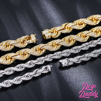 Close-up of Drip Daddy’s Avalanche Rope chains in yellow gold plated and white gold plated moissanite, laid flat in a display set with box clasps visible, shown against a black surface with the Drip Daddy logo in pink at the bottom right.