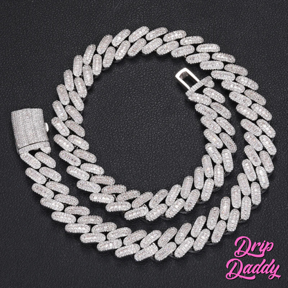 Drip Daddy’s Capsule – Mixed-Cut Cuban Chain in 14mm white gold plating, displayed coiled on a black textured background with its diamond-encrusted clasp. The Drip Daddy logo appears in pink at the bottom right.