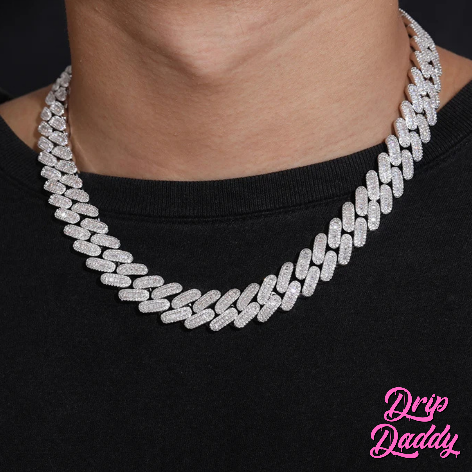 A person wearing Drip Daddy’s Capsule – Mixed-Cut Cuban Chain in 14mm white gold plating over a black shirt. The diamond-encrusted design sparkles under lighting, with the Drip Daddy logo in pink at the bottom right.