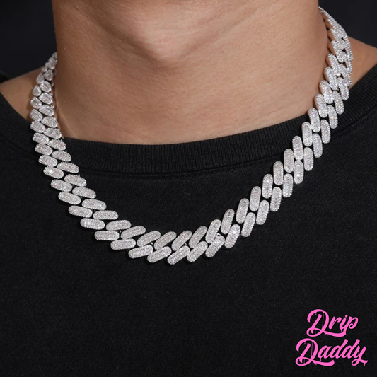 A person wearing Drip Daddy’s Capsule – Mixed-Cut Cuban Chain in 14mm white gold plating over a black shirt. The diamond-encrusted design sparkles under lighting, with the Drip Daddy logo in pink at the bottom right.