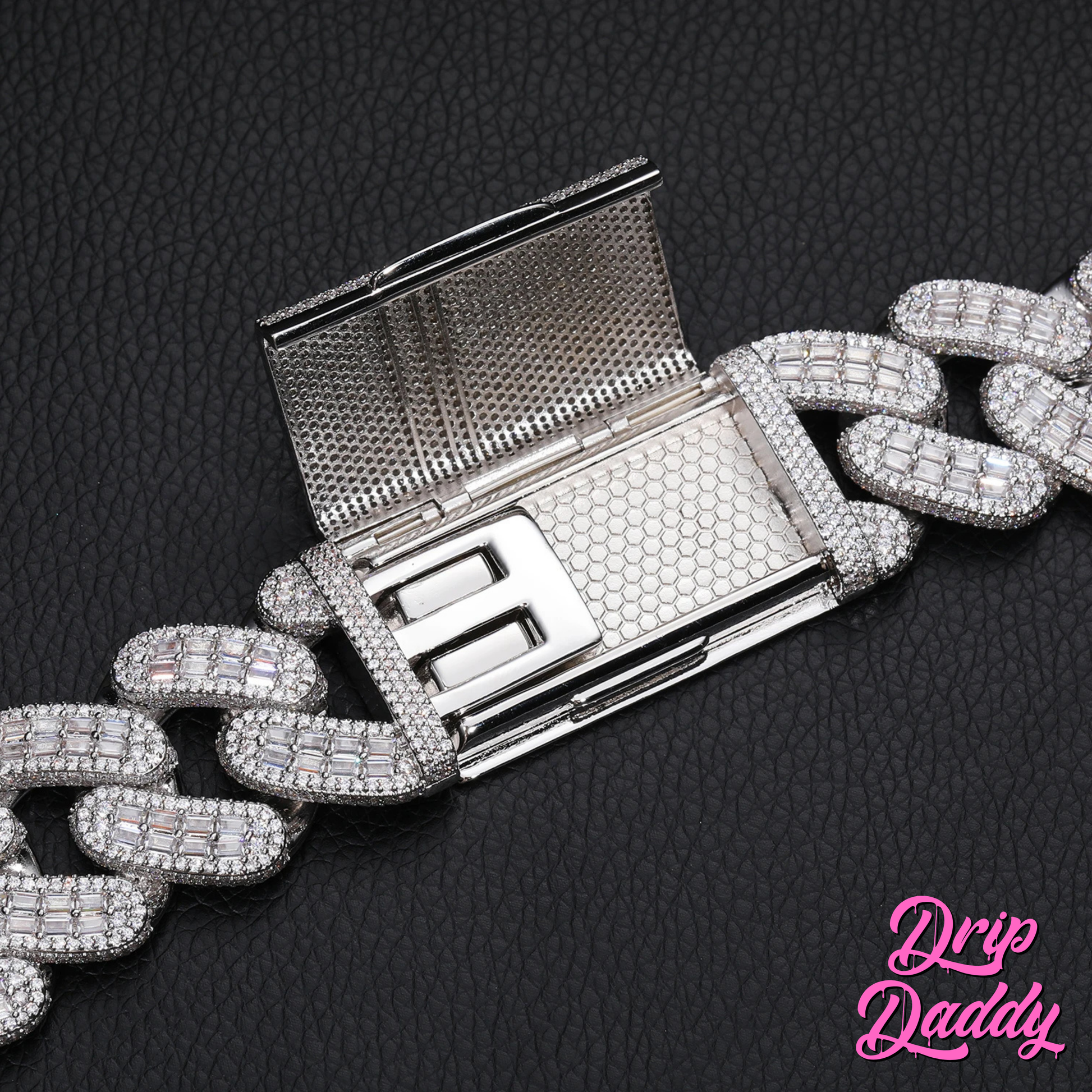 Close-up of Drip Daddy’s Capsule – Mixed-Cut Cuban Chain in 28mm white gold plating, showcasing the clasp open with diamond detailing. The black textured background features the Drip Daddy logo in pink at the bottom right.