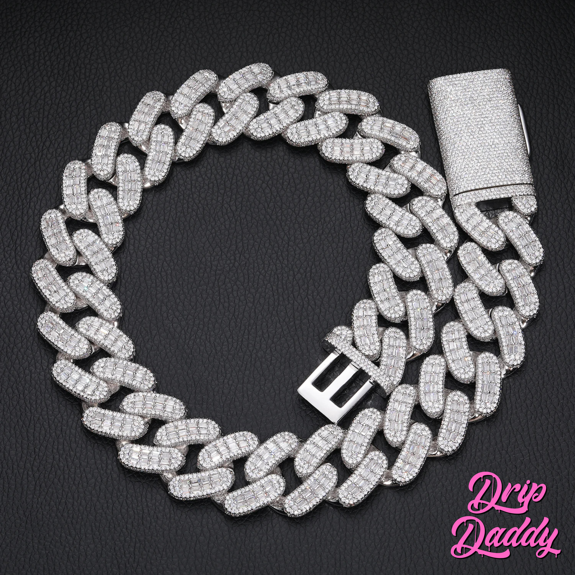 Drip Daddy’s Capsule – Mixed-Cut Cuban Chain in 28mm white gold plating, displayed coiled on a black textured surface with its diamond-studded clasp visible. The Drip Daddy logo is placed in pink at the bottom right.