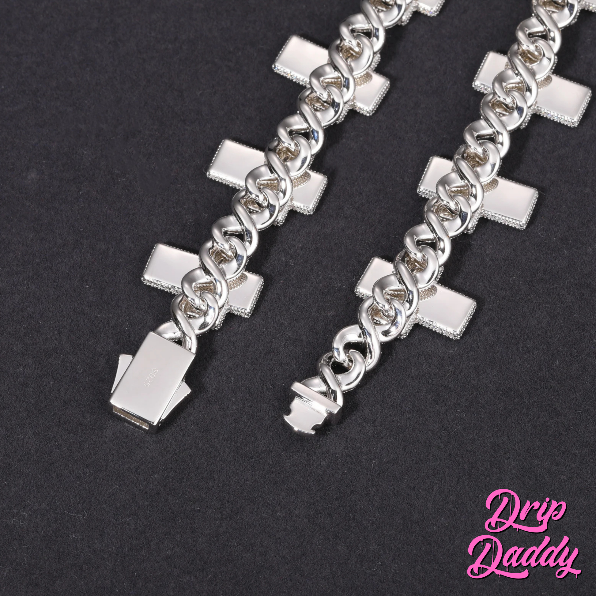 Close-up of Drip Daddy’s Crucifix Link – 8mm Moissanite Chain in white gold plating, showing the polished reverse side of the crucifix links and clasp design against a black background, with the pink Drip Daddy logo in the bottom right corner.