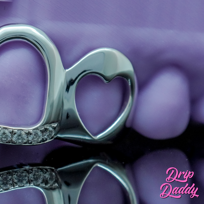 Drip Daddy Cut-Out Grillz featuring a silver heart design, set against a purple background and watermarked with the Drip Daddy logo.