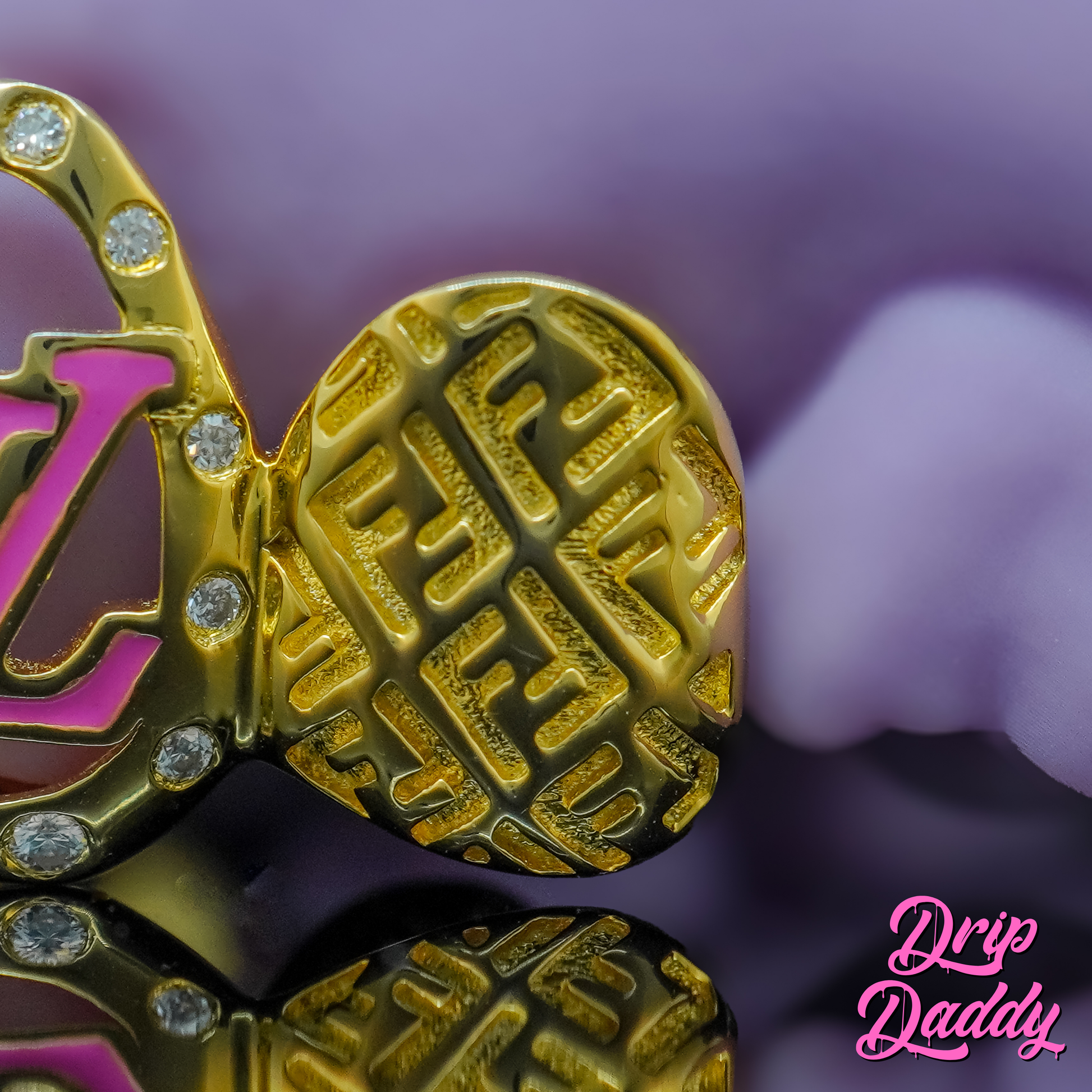 Close-up of a custom gold grillz tooth cap by Drip Daddy, featuring an engraved Fendi-inspired pattern with round stone details. Luxury gold grillz design displayed against a purple background with Drip Daddy logo.