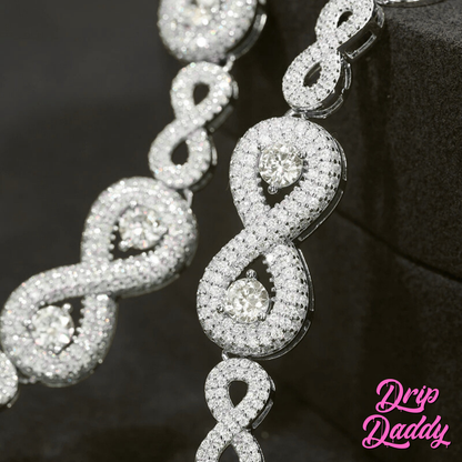 Close-up of Drip Daddy’s Eternal Drip – 12mm Moissanite Chain in white and yellow gold plating draped vertically to highlight the interlocking infinity-style links and round-cut center stones, with the Drip Daddy logo in pink visible in the bottom right corner.