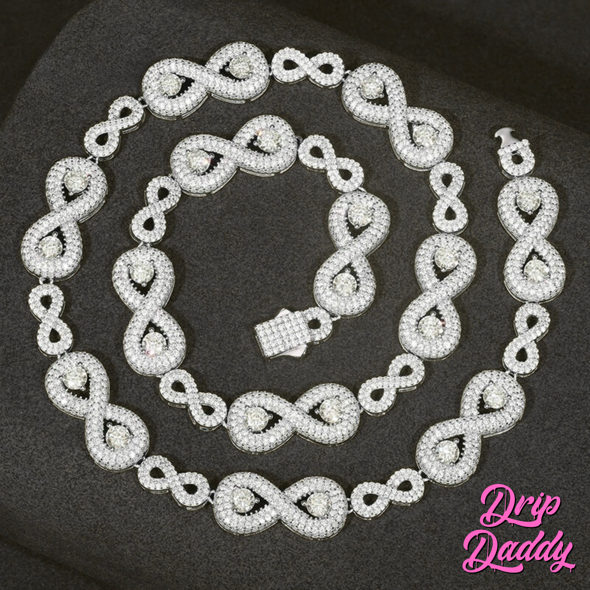A display of Drip Daddy’s Eternal Drip – 12mm Moissanite Chain in white and yellow gold plating laid out in a matching necklace and bracelet set on a dark textured background, with the Drip Daddy logo in pink visible in the bottom right corner.