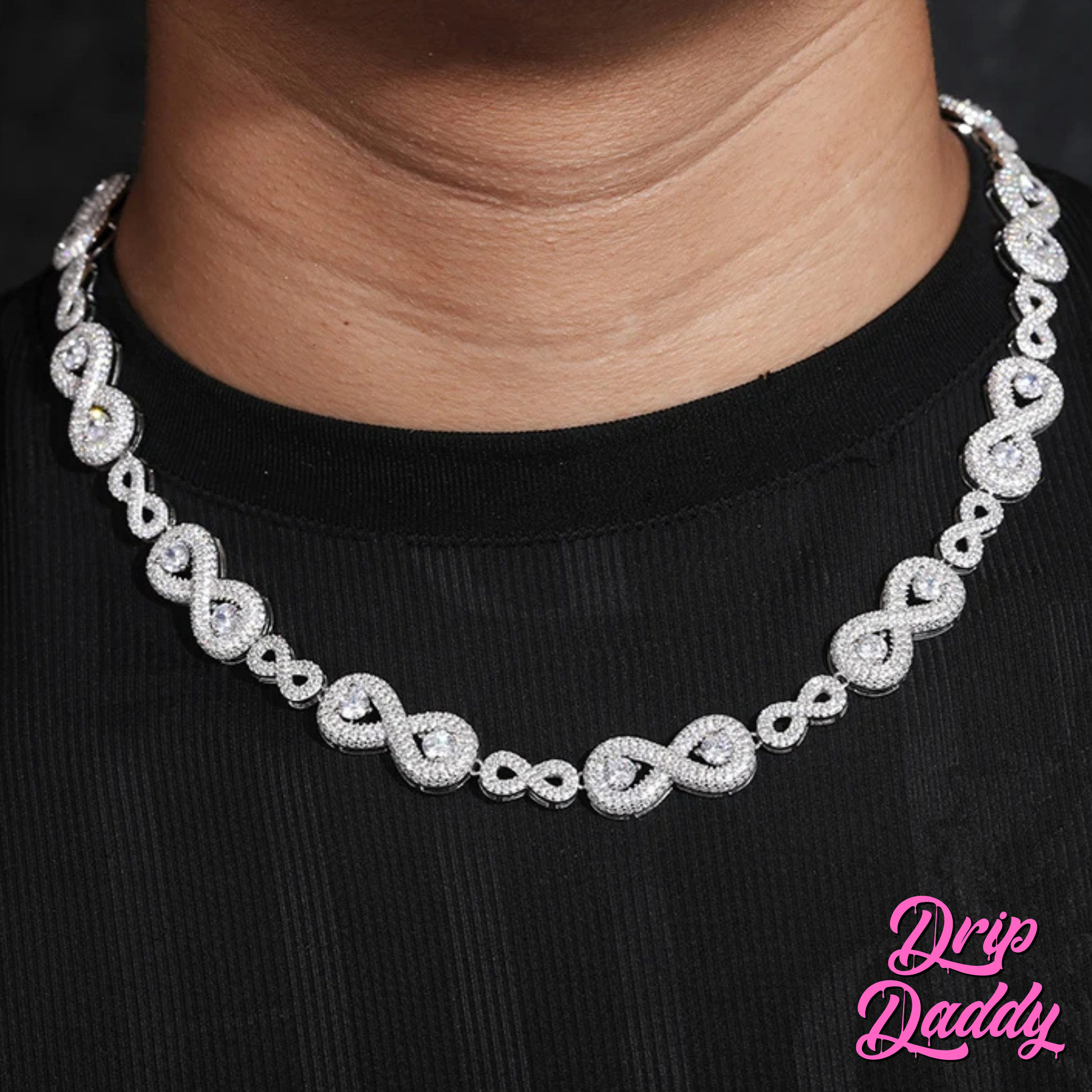 A person wearing Drip Daddy’s Eternal Drip – 12mm Moissanite Chain in white and yellow gold plating styled over a black shirt, with the Drip Daddy logo in pink visible in the bottom right corner.