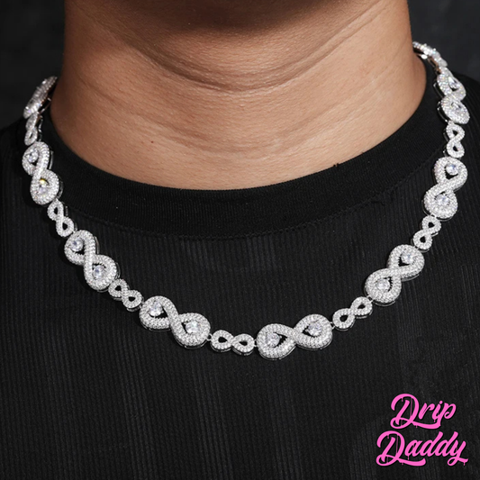 A person wearing Drip Daddy’s Eternal Drip – 12mm Moissanite Chain in white and yellow gold plating styled over a black shirt, with the Drip Daddy logo in pink visible in the bottom right corner.