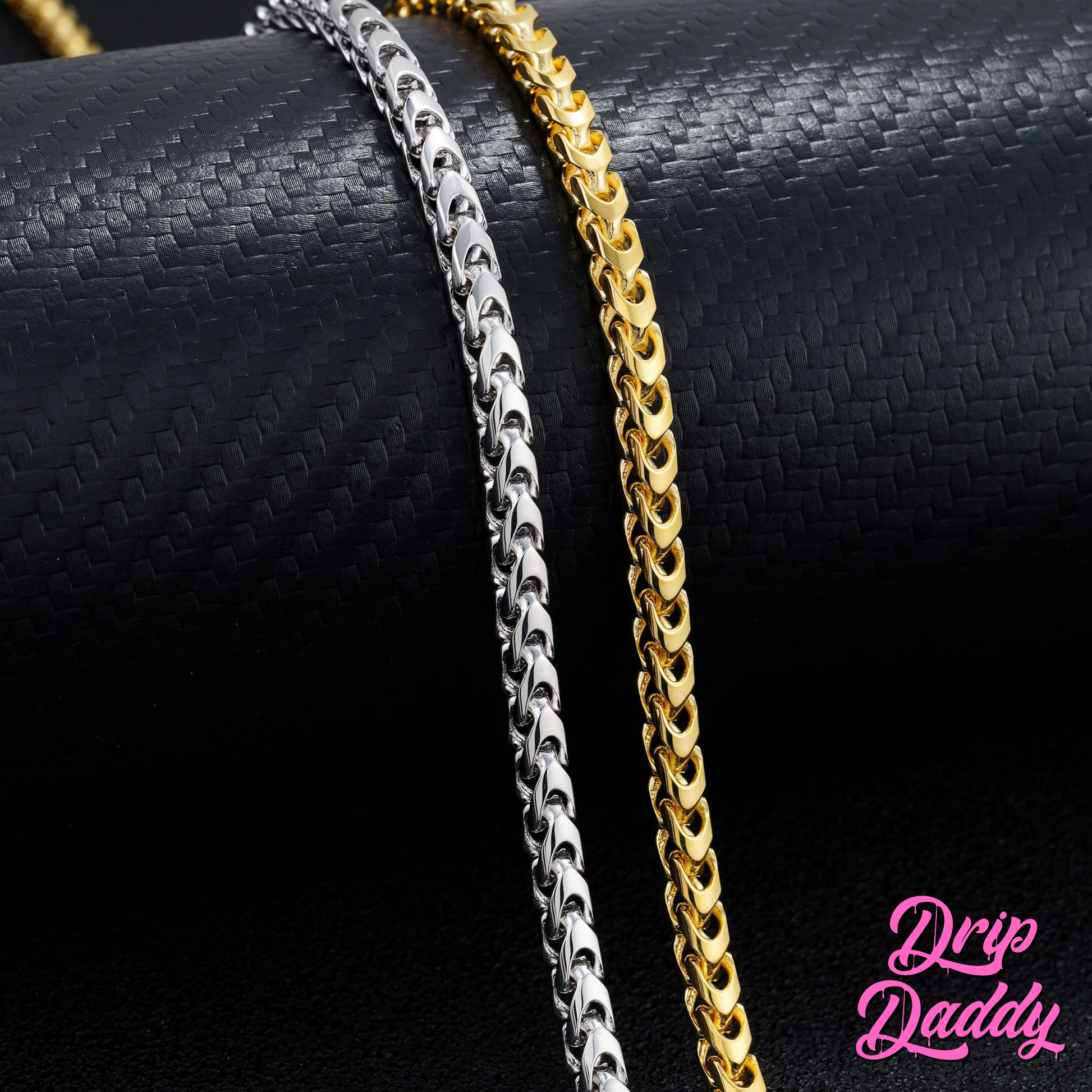Close-up of Drip Daddy’s Franco Flex 4mm Franco Chains in yellow gold plating and white gold plating shown side by side, displayed on a textured black surface, with the pink Drip Daddy logo visible in the bottom right corner.