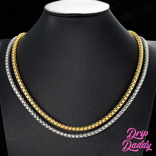 Display of Drip Daddy’s Franco Flex 4mm Franco Chains in yellow gold plating and white gold plating layered on a black mannequin neck, with the pink Drip Daddy logo visible in the bottom right corner.