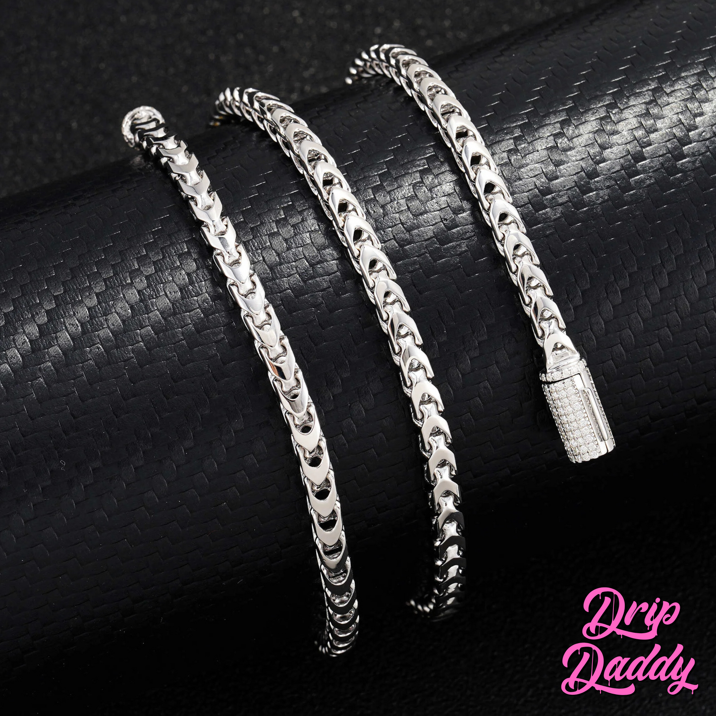 Close-up of Drip Daddy’s Franco Flex 4mm Franco Chain in white gold plating with an iced-out moissanite clasp, displayed on a textured black surface, with the pink Drip Daddy logo visible in the bottom right corner.