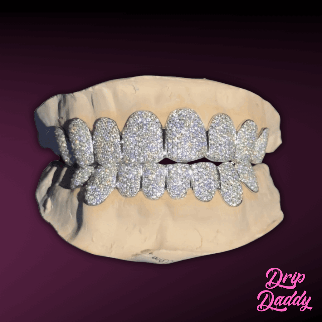 Luxury iced out grillz from Drip Daddy, designed in 925 sterling silver and covered with moissanite stones for a full diamond look. Displayed on a plaster mold with a dark purple background, perfect for hip hop jewelry styling.