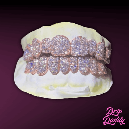 Custom iced out grillz by Drip Daddy, crafted in 925 sterling silver with rose gold plating and encrusted with moissanite stones. Luxury diamond-like brilliance, displayed on a dental mold with a dark gradient background.
