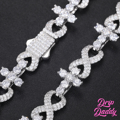 Close-up of the clasp detail on Drip Daddy’s Infinity Link bracelet in white gold with iced-out moissanite stones, shown on a black background with the pink Drip Daddy logo visible in the corner.