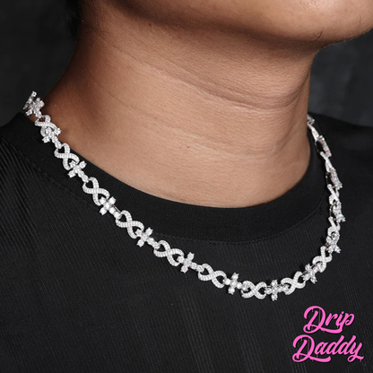 A person wearing Drip Daddy’s Infinity Link necklace in white gold with iced-out moissanite stones, styled over a black shirt, with the pink Drip Daddy logo visible in the corner.