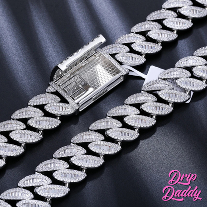 Close-up of the clasp of Drip Daddy’s The Enforcer 20mm Mixed-Cut Cuban Link Chain in white gold with diamond detailing, displayed on a dark fabric background with the Drip Daddy logo in pink at the bottom right corner.