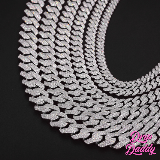 Multiple Moissanite Cuban Link Chains (8mm to 18mm, white & yellow gold plated) by Drip Daddy are arranged in a curve on a black background, with the Drip Daddy logo in pink at the bottom right.