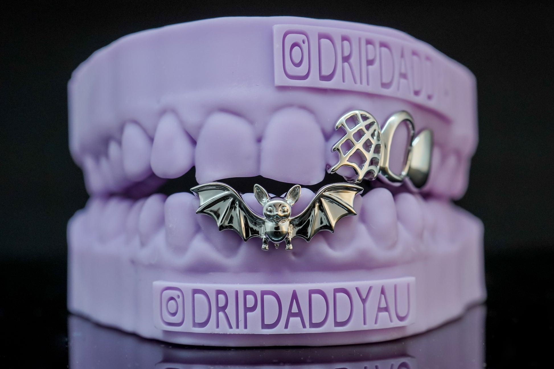 Unique silver bat grillz with spiderweb detail, handcrafted by Drip Daddy, shown on purple dental model.