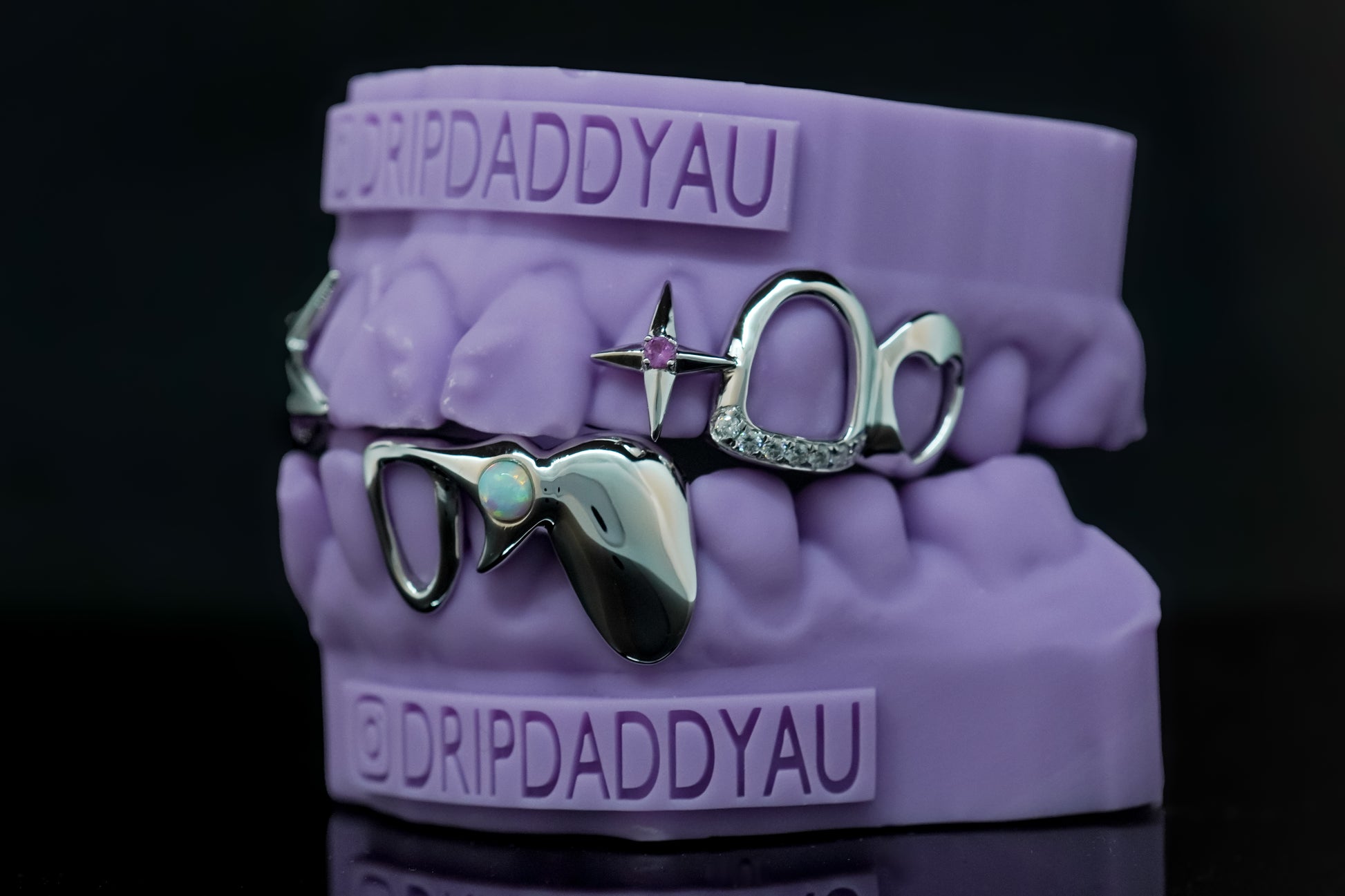 Custom silver grillz with opal stone, star detail, and heart cutouts by Drip Daddy, displayed on purple dental mold.