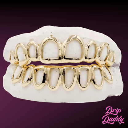 Custom Open Face Window Grillz in yellow-gold plating on 925 sterling silver, full upper and lower set on a dental mold, shown against a purple gradient with the Drip Daddy logo.