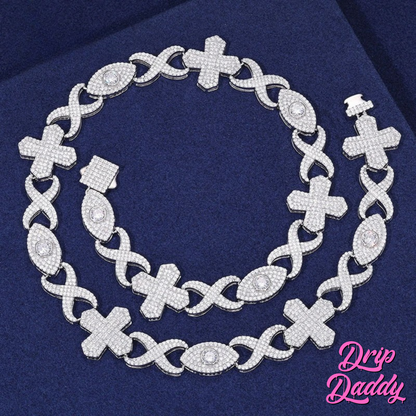 The Drip Daddy Evil Eye Cross Link – 12mm Moissanite Chain in full view, featuring alternating cross and eye-shaped links with moissanite stones, displayed on a dark blue fabric background.