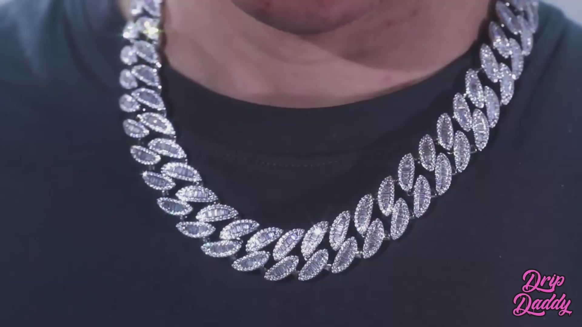 A rotating showcase of Drip Daddy’s Enforcer – 20mm Mixed-Cut Cuban Link Chain in white gold plating. The video highlights alternating emerald-cut and round moissanite stones set across the chain, with light reflections emphasizing the sparkle. The Drip Daddy logo appears in pink at the bottom right corner throughout the clip.