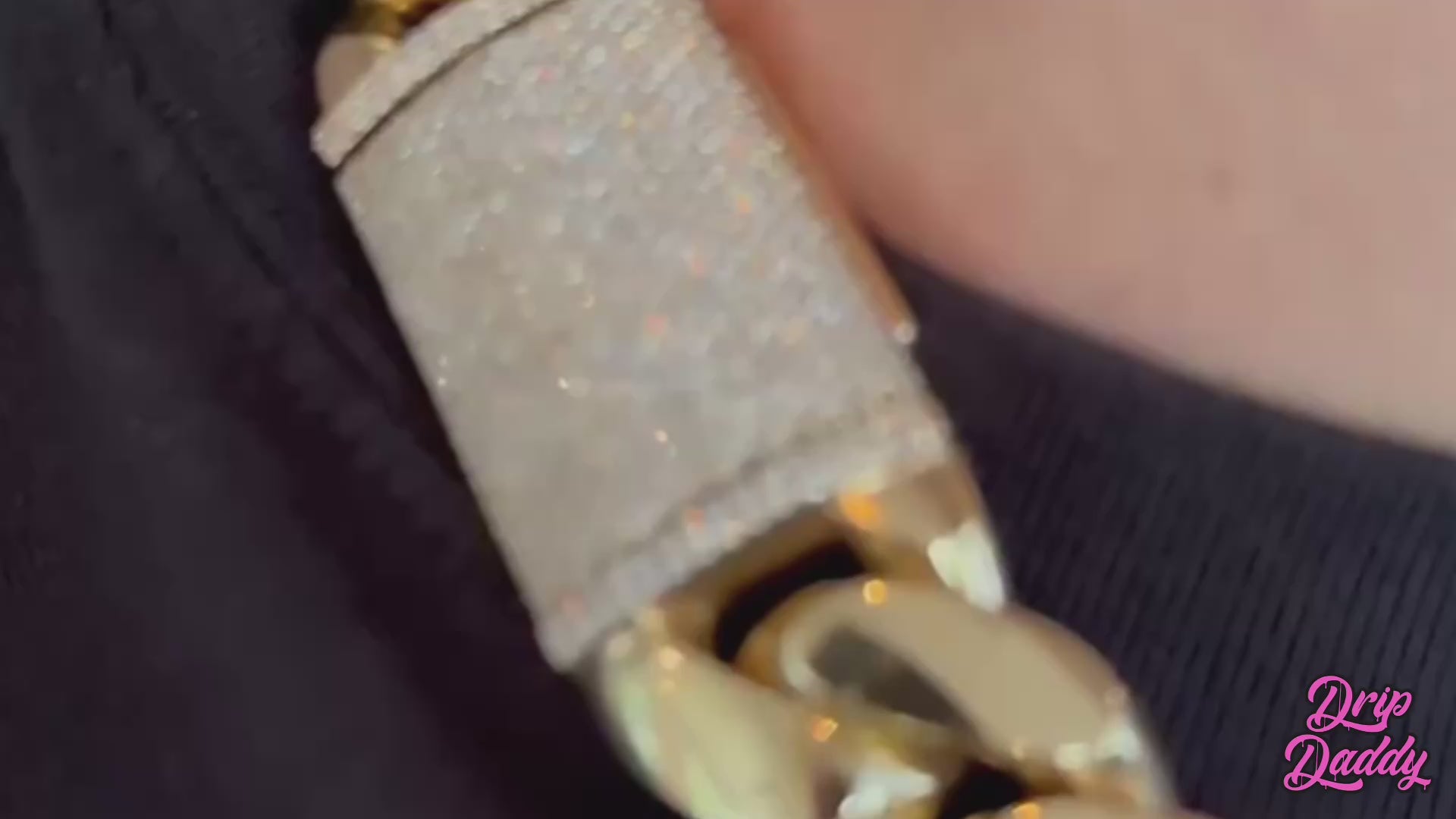 A person wearing Drip Daddy’s The Don – 20mm to 30mm Miami Cuban Link Chain in polished white and yellow gold plating, shown in a lifestyle model video. The chain is thick and bold, capturing light with its reflective surface and heavyweight design. The Drip Daddy logo in pink is displayed in the corner of the video frame.