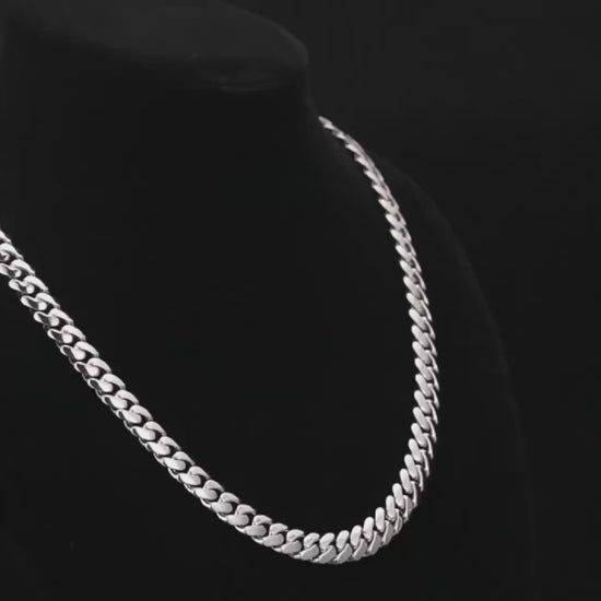 A rotating video display of Drip Daddy’s The Hustler Cuban Link Chain, available in 8mm to 15mm widths, crafted in white gold plating. The video showcases the thick interlocking Cuban links from multiple angles under professional lighting, highlighting the polished metallic finish and bold design. The Drip Daddy logo in pink is visible on-screen throughout the video.