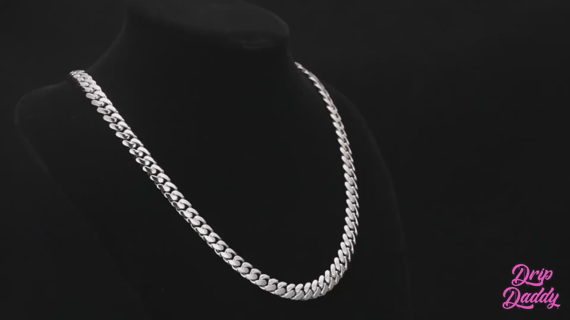 A rotating video display of Drip Daddy’s The Hustler Cuban Link Chain, available in 8mm to 15mm widths, crafted in white gold plating. The video showcases the thick interlocking Cuban links from multiple angles under professional lighting, highlighting the polished metallic finish and bold design. The Drip Daddy logo in pink is visible on-screen throughout the video.